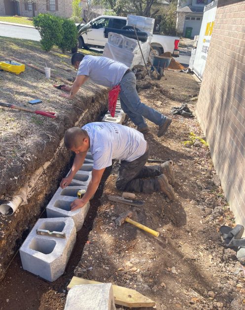 Workers laying down cinderblocks for retaining wall