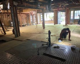 Maestro's Foundation Repair employee nailing down wood flooring to beams